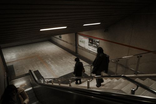 Free People walking down subway stairs in an urban setting, captured with ambient lighting. Stock Photo