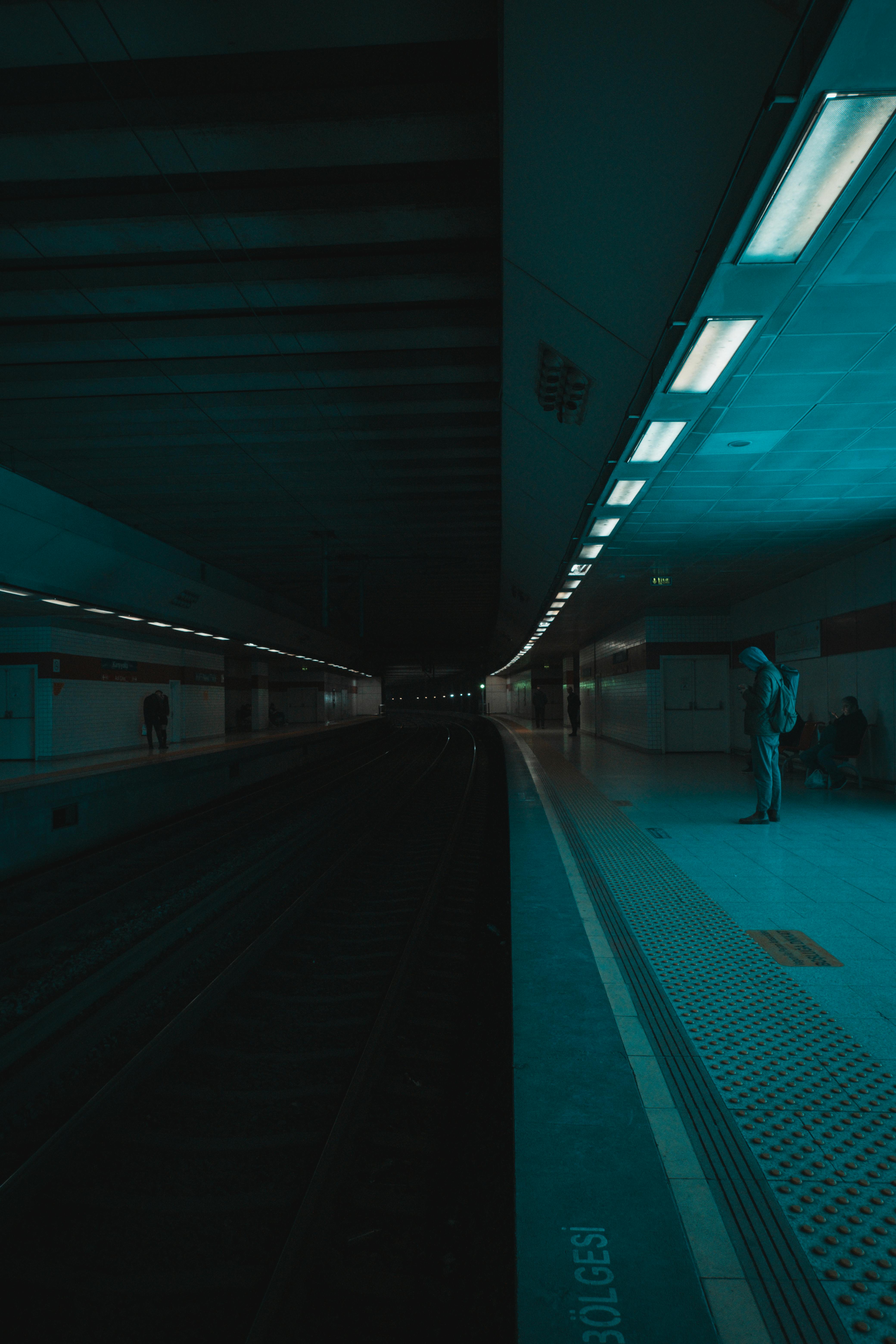 A quiet, dimly lit subway platform with a solitary commuter captured in a moody atmosphere.