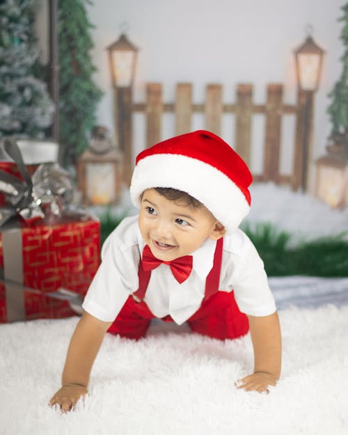 Little Boy in a Santa Hat under a Christmas Tree 