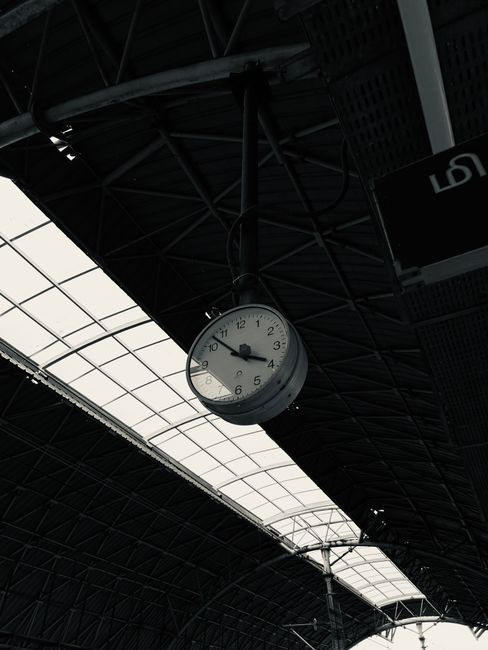 Monochrome image of a clock hanging in Chennai railway station, highlighting urban transit.