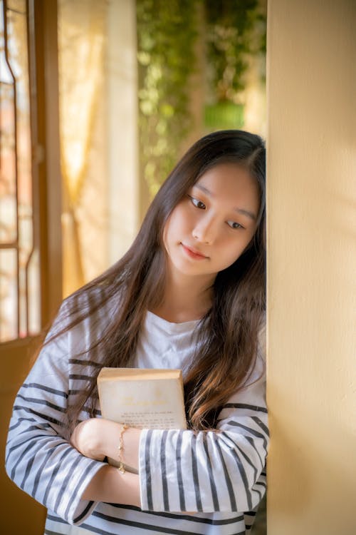 Woman Standing with Book and Leaning on Wall