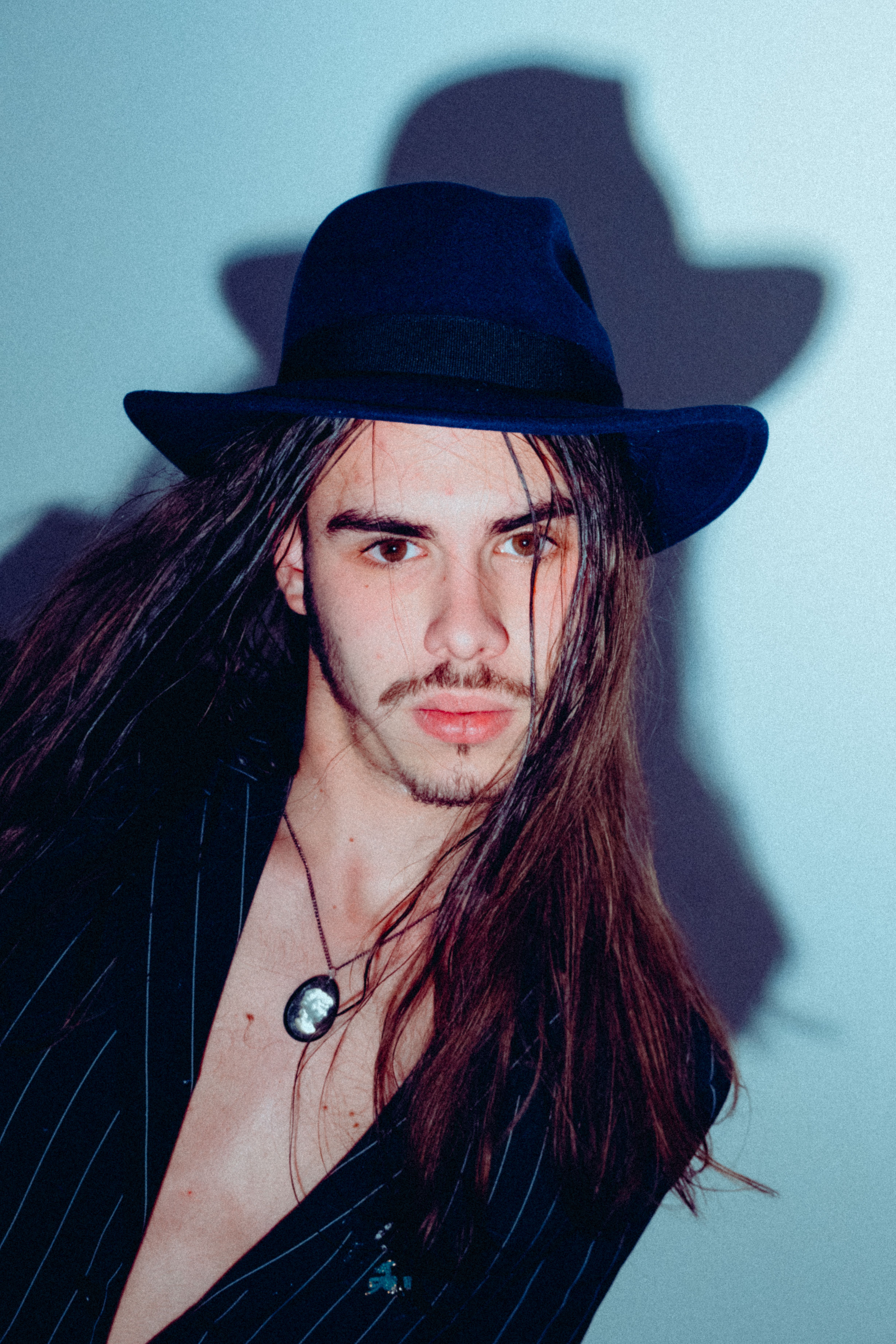 Portrait of a fashionable man with long hair and a hat, showcasing modern style.