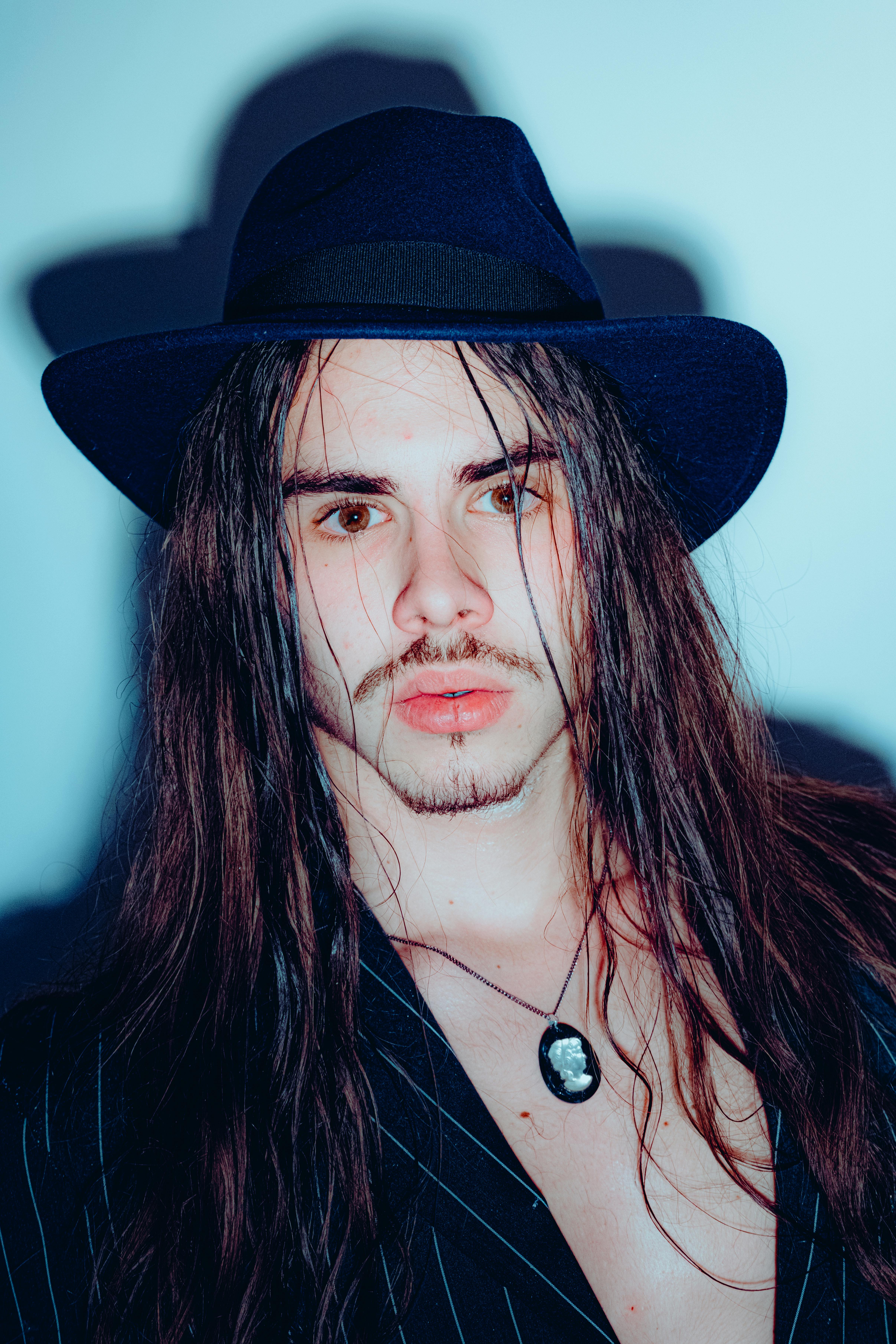 Elegant man with long hair and hat, showcasing modern style in Brașov.