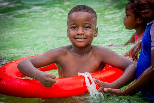 Smiling child with friends enjoying a summer swim with an inflatable ring.