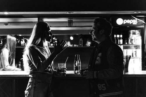 Free Monochrome photo of a man and woman talking at a bar, capturing an intimate social moment. Stock Photo