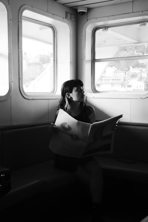 Woman Reading Newspaper in a Train in Black and White 