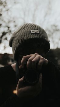 A young photographer focusing through a camera lens outdoors in İstanbul.