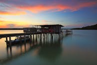 木制码头、船只和平静的海水，与宁静的日落景色共同营造出宁静的氛围