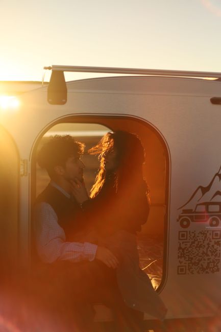 Couple embracing in a camper van during a warm sunset, showcasing affection and wanderlust.