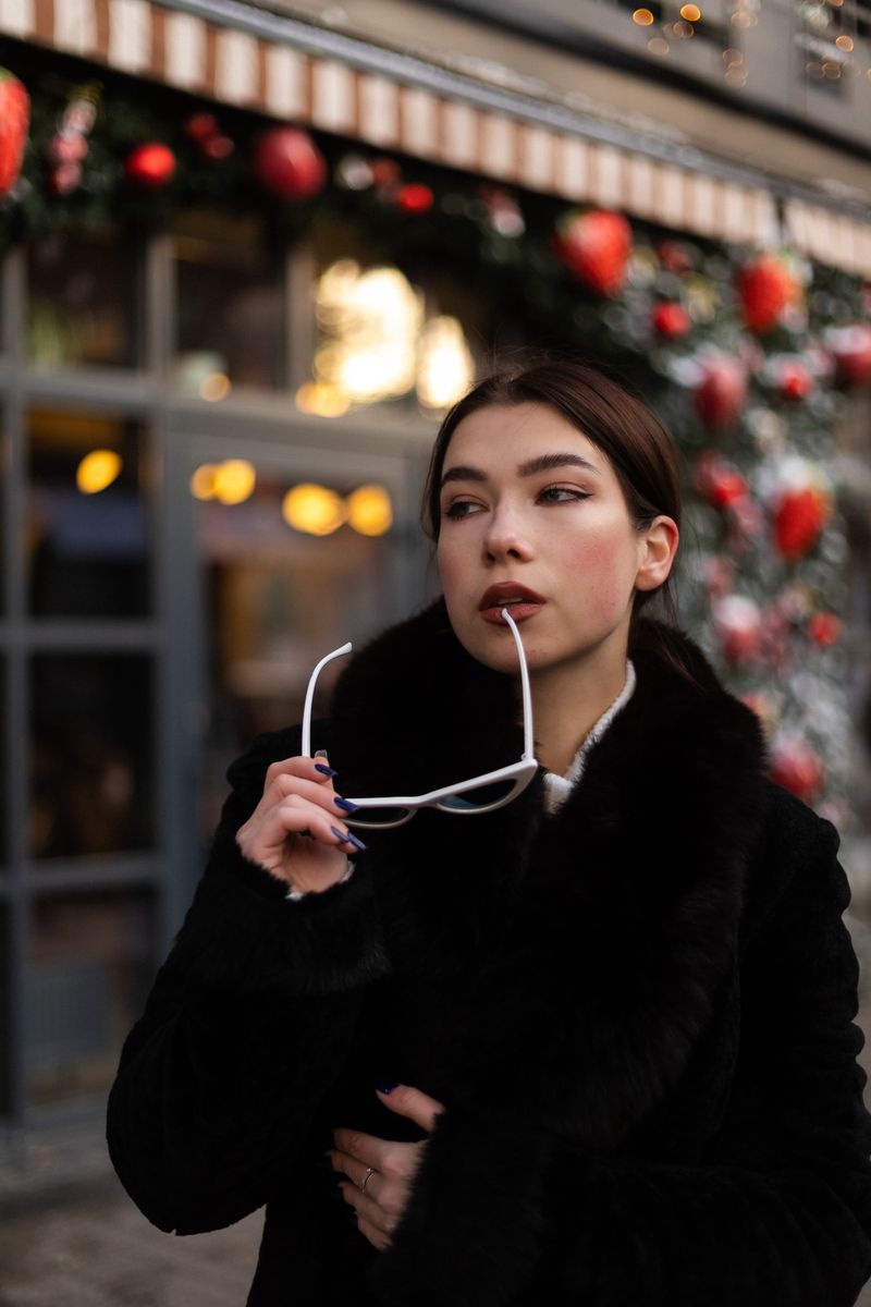 Woman in a black coat and sunglasses in a winter setting