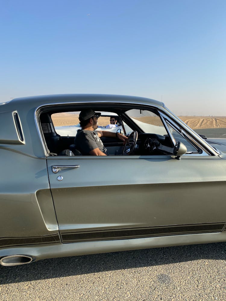 Man Driving A Black Car On A Road 