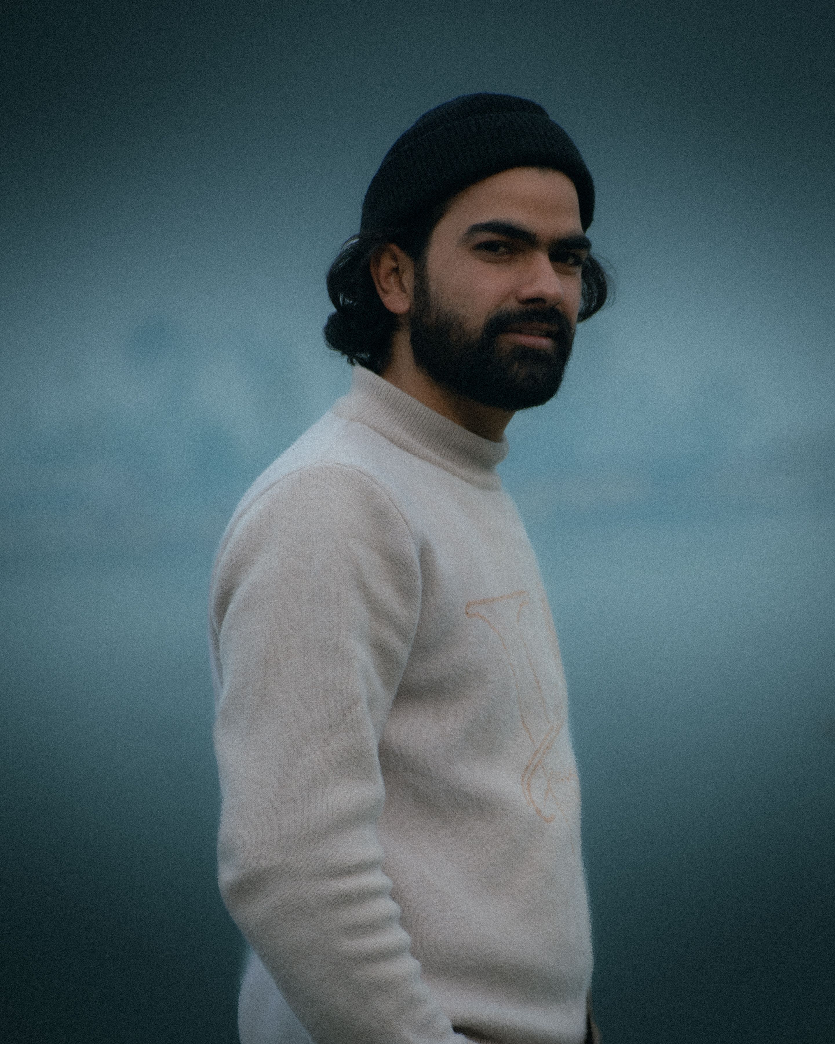 Portrait of a fashionable man with a beard wearing knitwear outdoors.