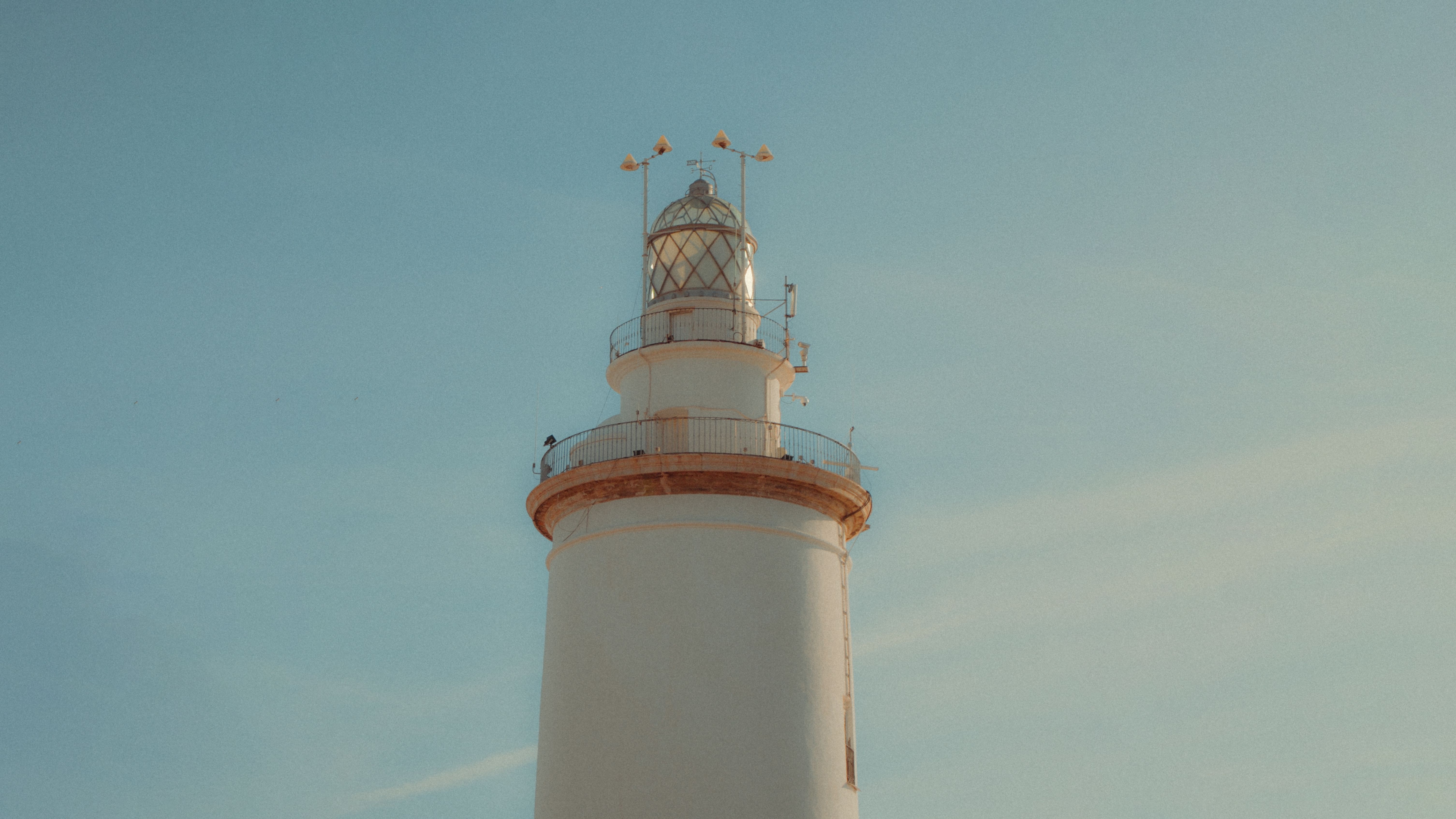 A stunning view of Málaga's iconic lighthouse under a clear blue sky, perfect for travel and architecture themes. - Málaga