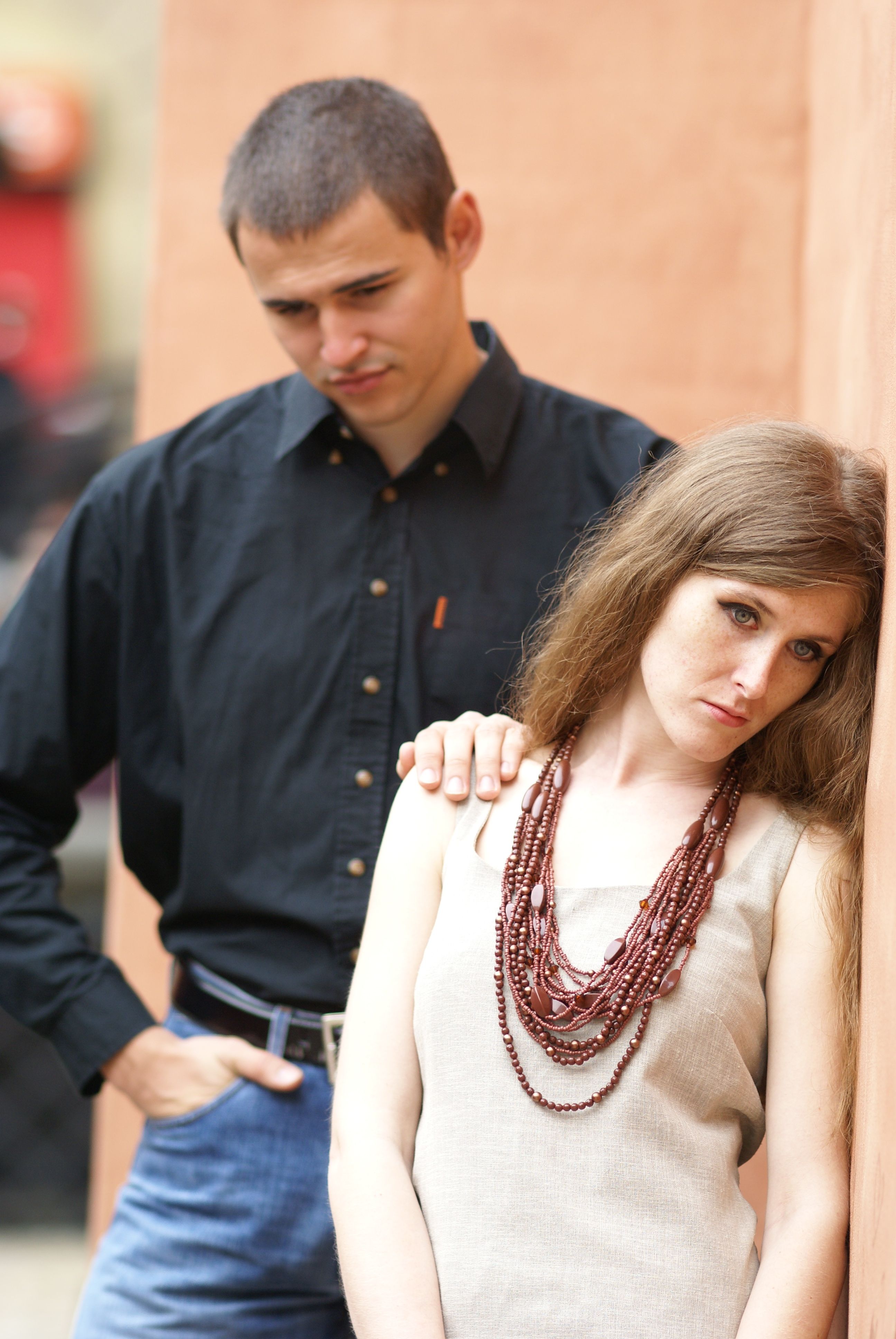 A thoughtful couple poses against a textured wall in an intimate and introspective moment.