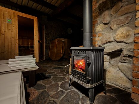 Warm sauna room in Płociczno featuring a classic wood-burning stove and rustic stone walls.