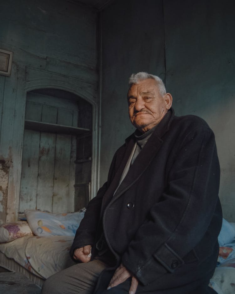 Portrait Of An Elderly Man Sitting On A Bed 