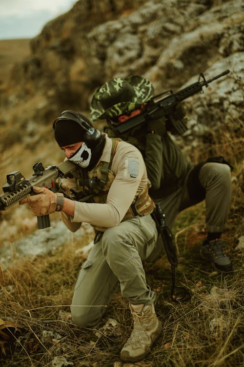 Foto profissional grátis de agachado, apontando, armas