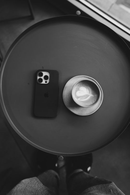 Free Stylish black and white flat lay of a latte and smartphone on a round table. Stock Photo