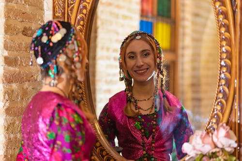 Smiling Woman in Traditional Clothing Standing by Mirror