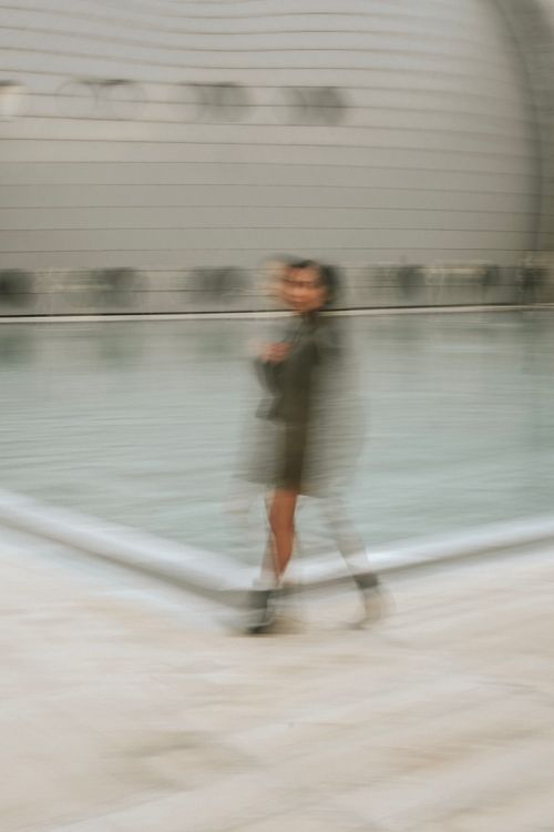 Free A creative motion blur capture of a woman posing beside a sleek modern pool, evoking elegance and mystery. Stock Photo
