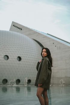 A woman stands confidently in front of modern architecture, embodying style and elegance.
