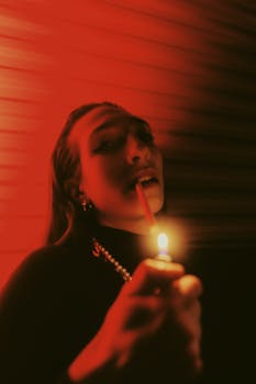 A dramatic, red-lit portrait of a woman holding a lighter, creating a cinematic effect.