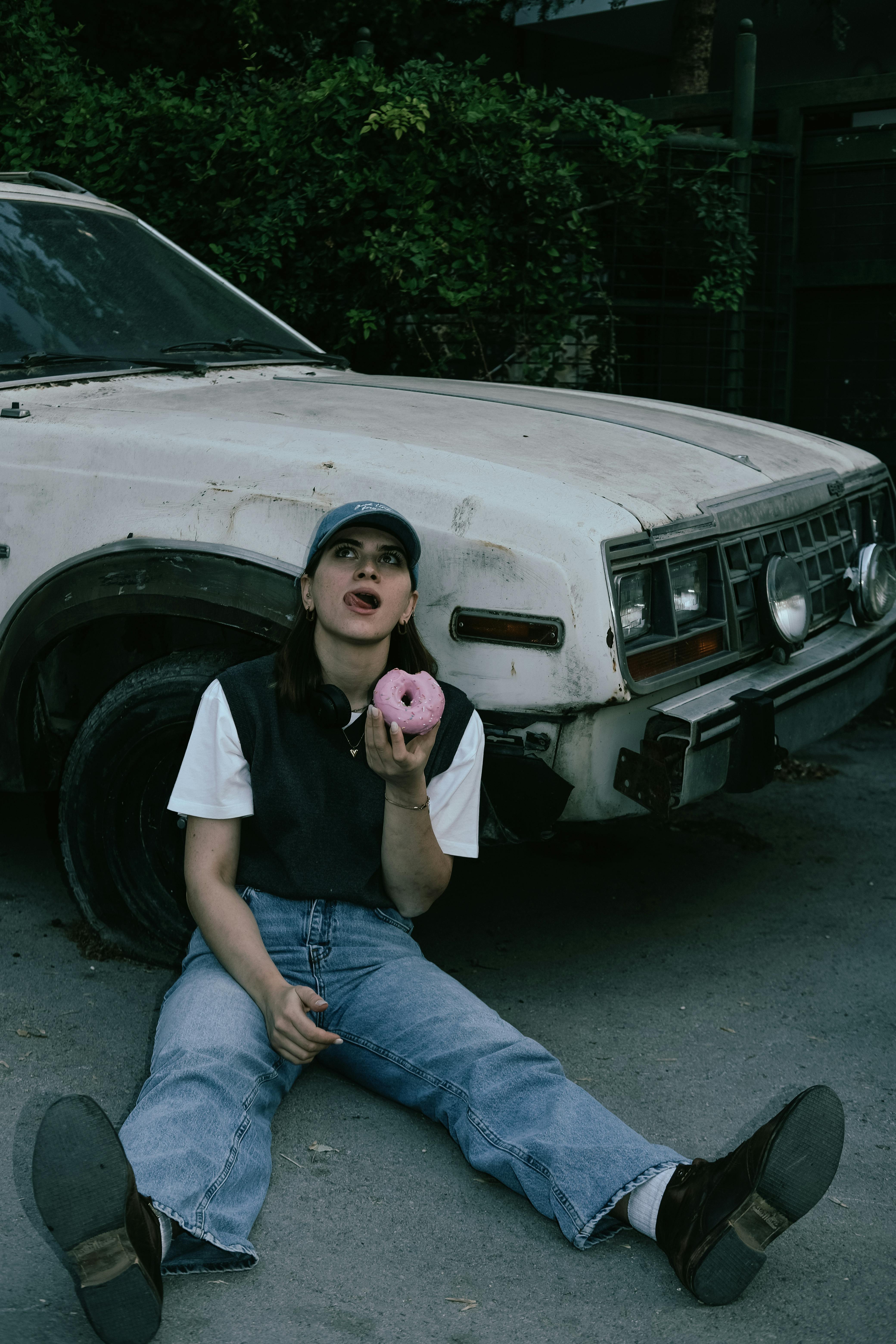 Woman Eating Donut in Front of a White Car · Free Stock Photo