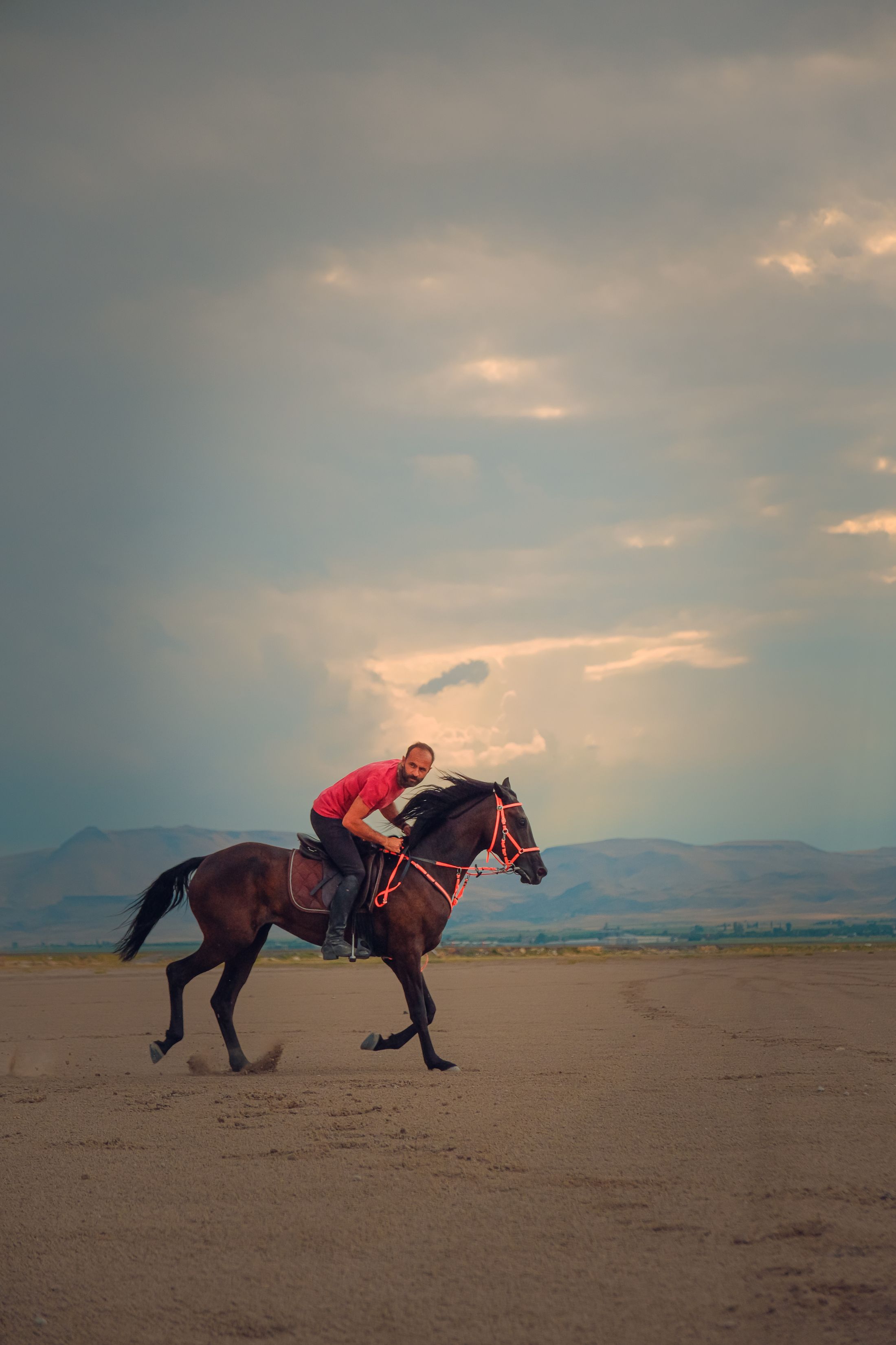 Horse rider crossing a sandy landscape at golden hour