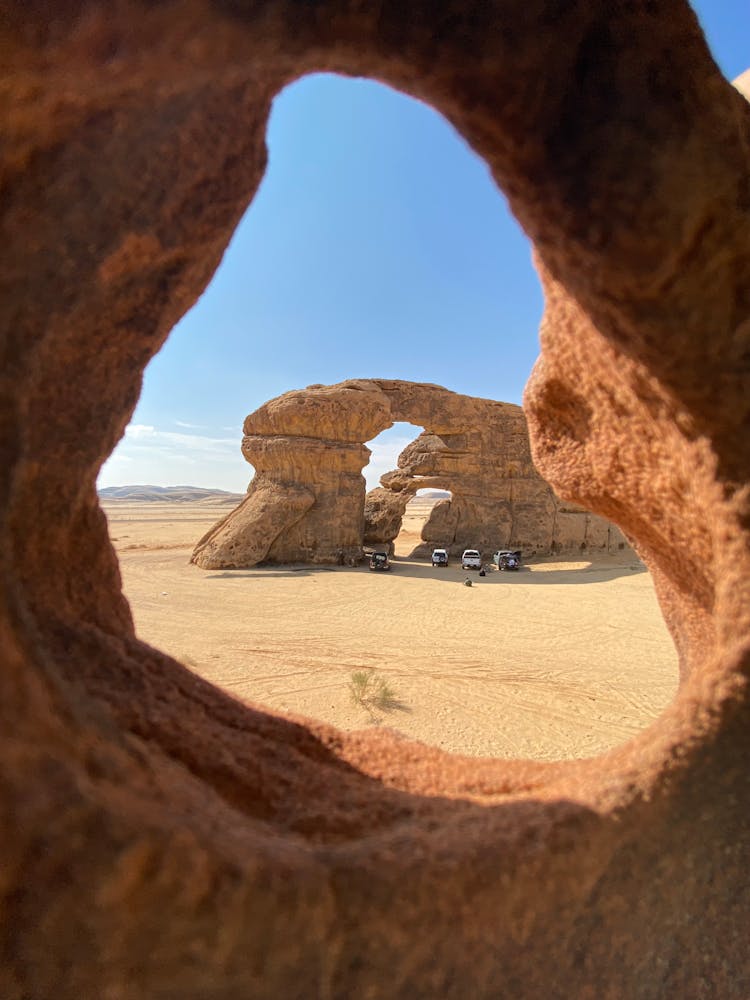 Cars Parked In The Shadow Of A Rock In The Desert