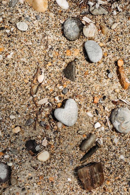 A heart shaped rock and pebbles on the beach