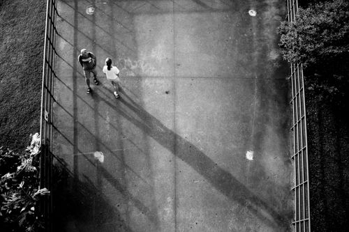 Free Top view of two people walking in black and white, with long shadows on pavement. Stock Photo