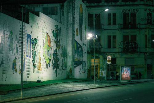 Free A vibrant urban street at night featuring a graffiti-covered wall, streetlights, and city buildings. Stock Photo