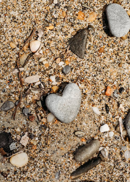 A heart shaped rock and pebbles on the beach