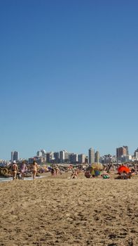 Sunny beach day in Mar del Plata with urban skyline backdrop, perfect for leisure and relaxation.