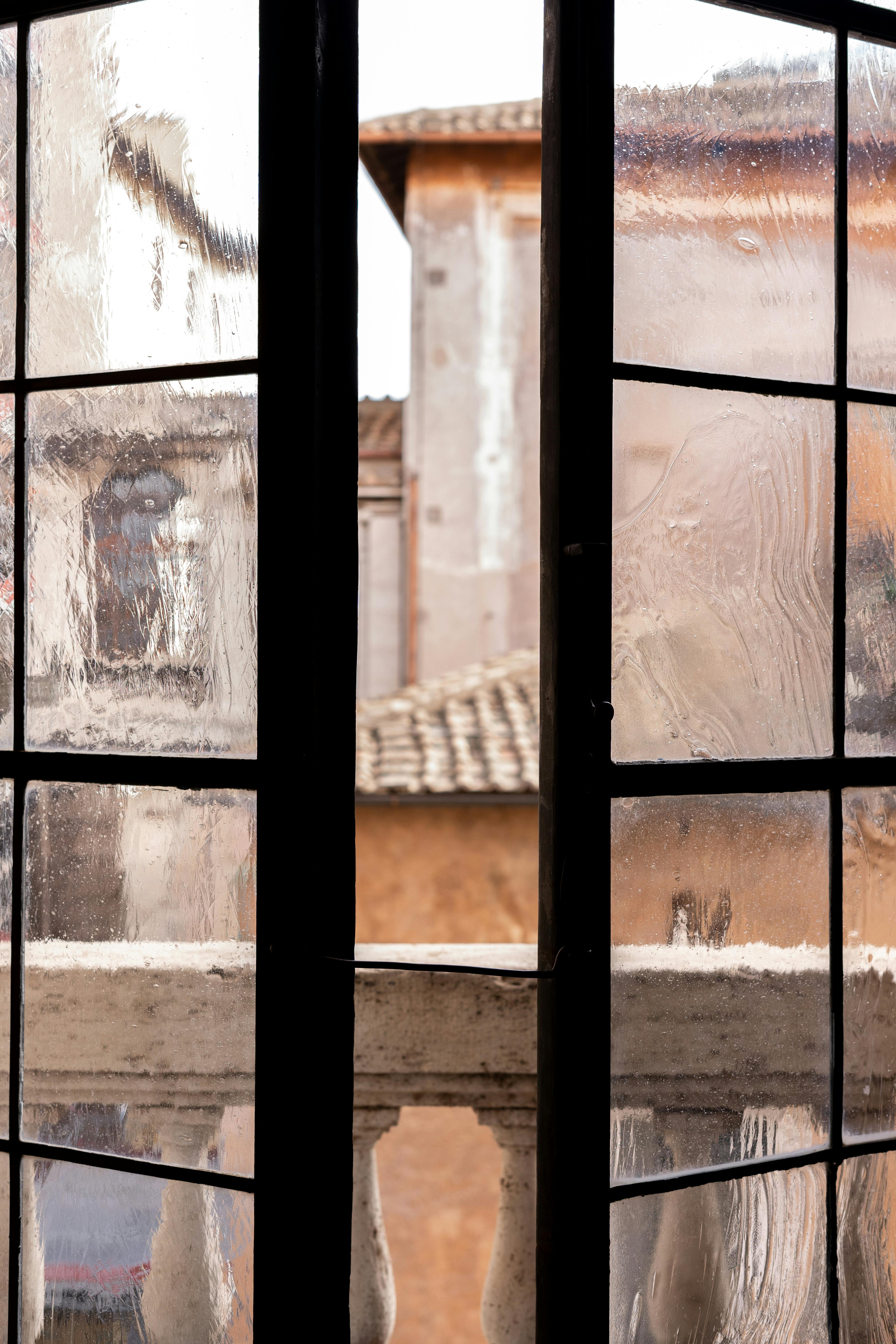 View of Rome's old architecture through a vintage glass window.