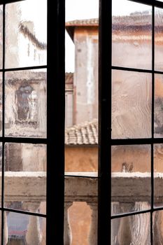 View of Rome's old architecture through a vintage glass window.