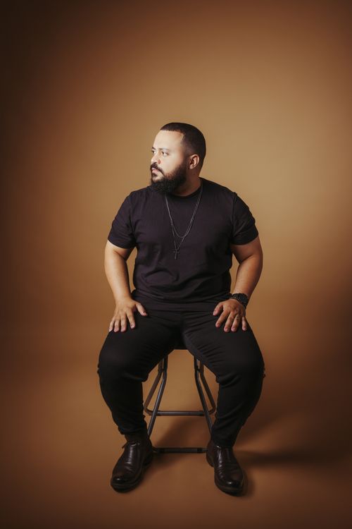 Free Portrait of a stylish male model in a fashion shoot, sitting and posing in a studio setting. Stock Photo