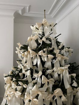 A beautifully decorated Christmas tree with luxurious white ribbons indoors.