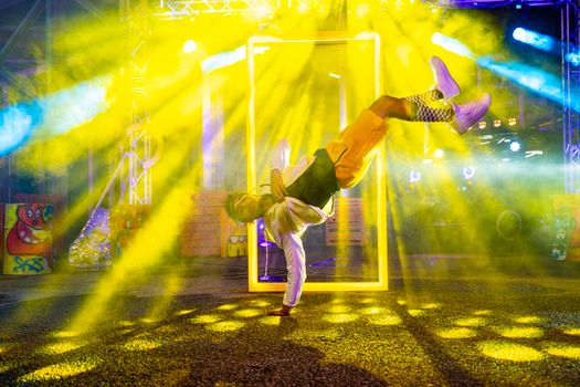 A talented dancer performing a breakdance move under vibrant neon lights.
