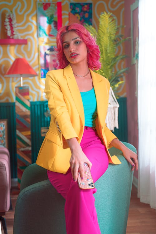 Young Woman with Pink Hair Wearing a Colorful Outfit and Sitting in a Colorful Room