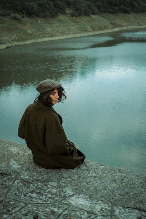 Woman in Coat Sitting by River