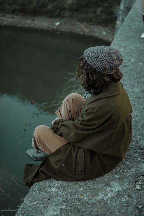 Brunette Woman in Coat Sitting by River