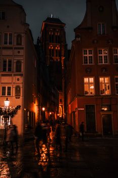 Illuminated streets of Gdansk Old Town at night, showcasing historic architecture and warm lights.
