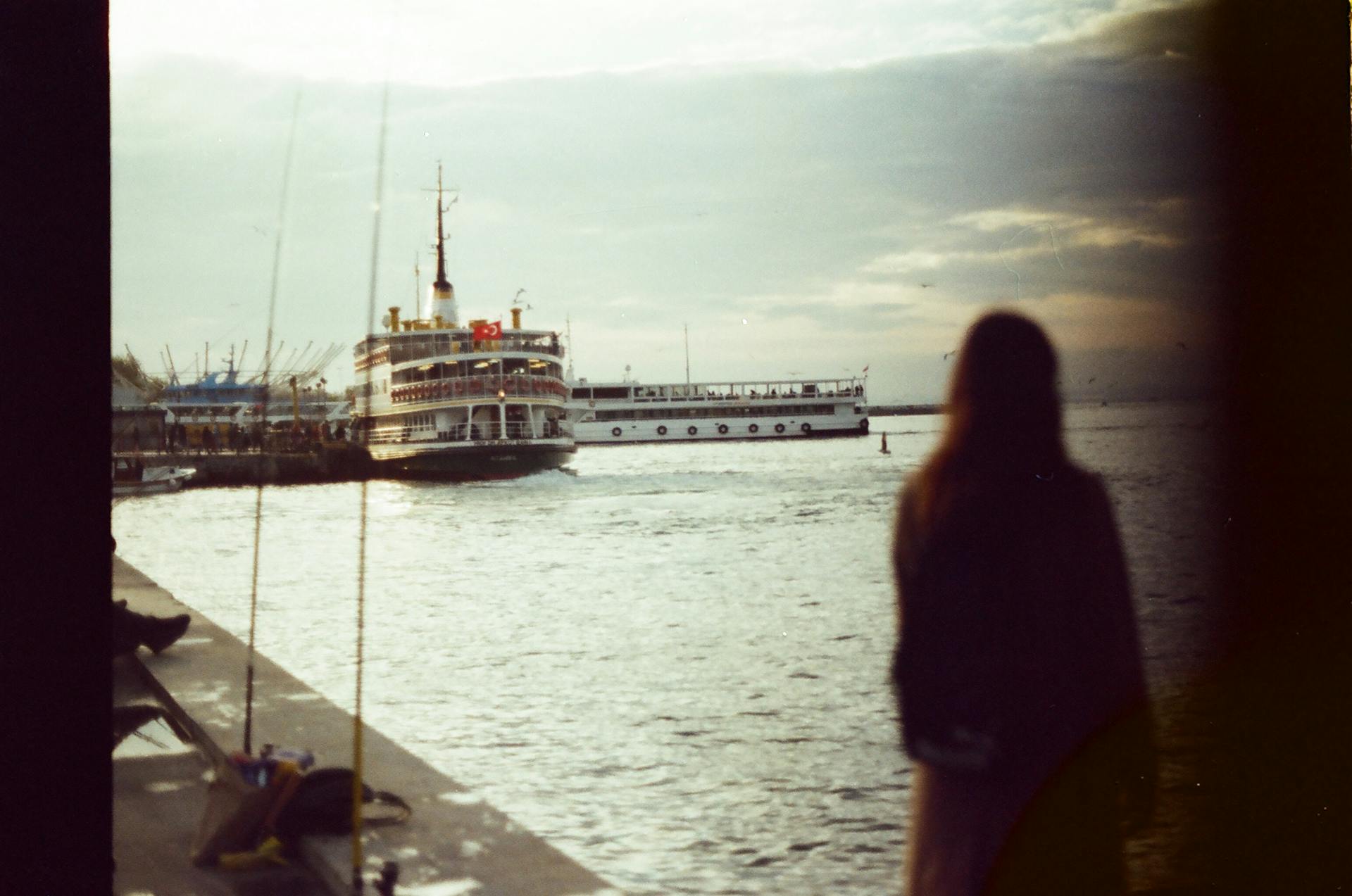 A tranquil scene of passenger ships at Istanbul port with a silhouetted figure in the foreground.