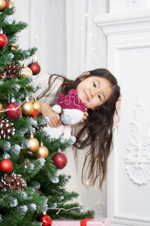 Portrait of a Little Girl Peeking from behind a Christmas Tree