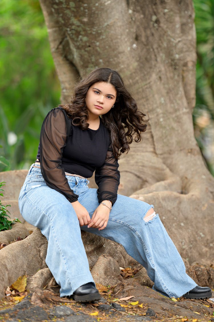 Young Girl In A Trendy Outfit Sitting Under A Tree