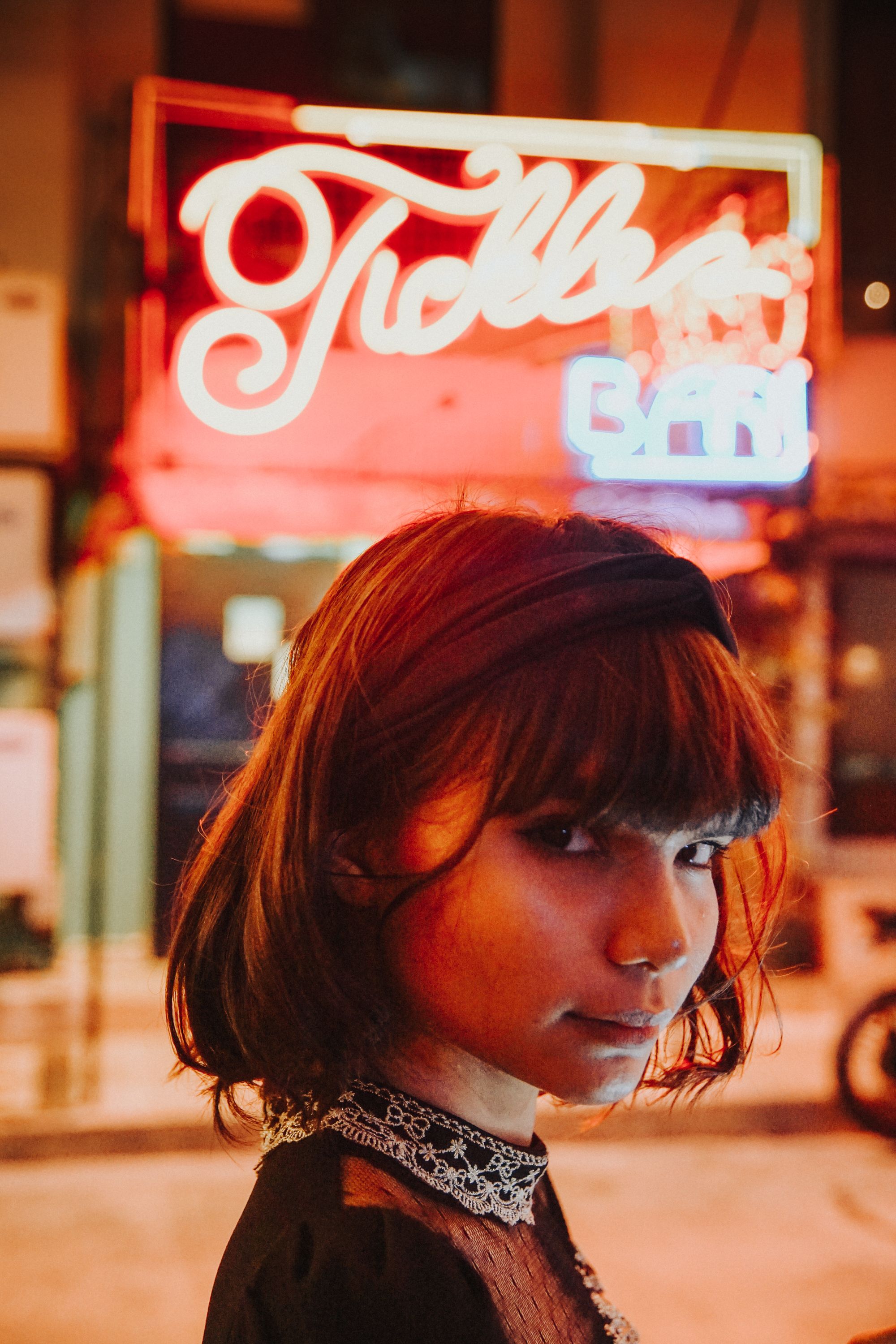 Young woman walking on illuminated street at night · Free Stock Photo