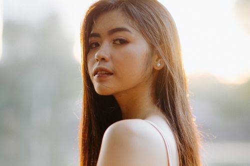 Free Portrait of a young woman with long hair and earrings, captured in soft natural light. Stock Photo