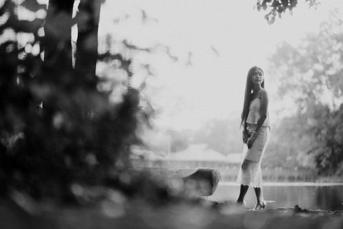 Free Elegant black and white portrait of a woman by a lakeshore with a serene background. Stock Photo