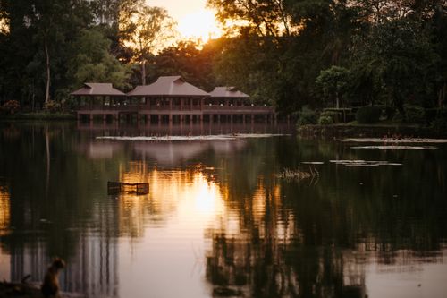 Free Tranquil sunset view of gazebos by a lake surrounded by lush trees. Stock Photo
